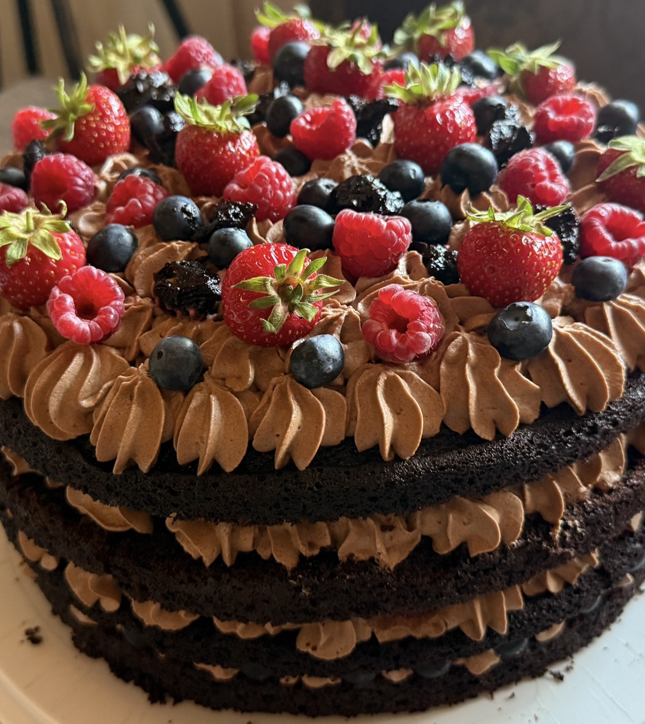 Chocolate cake with chocolate cream, strawberries, raspberries and blueberries